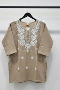 Brown outfit with white floral patterns on a tiled floor